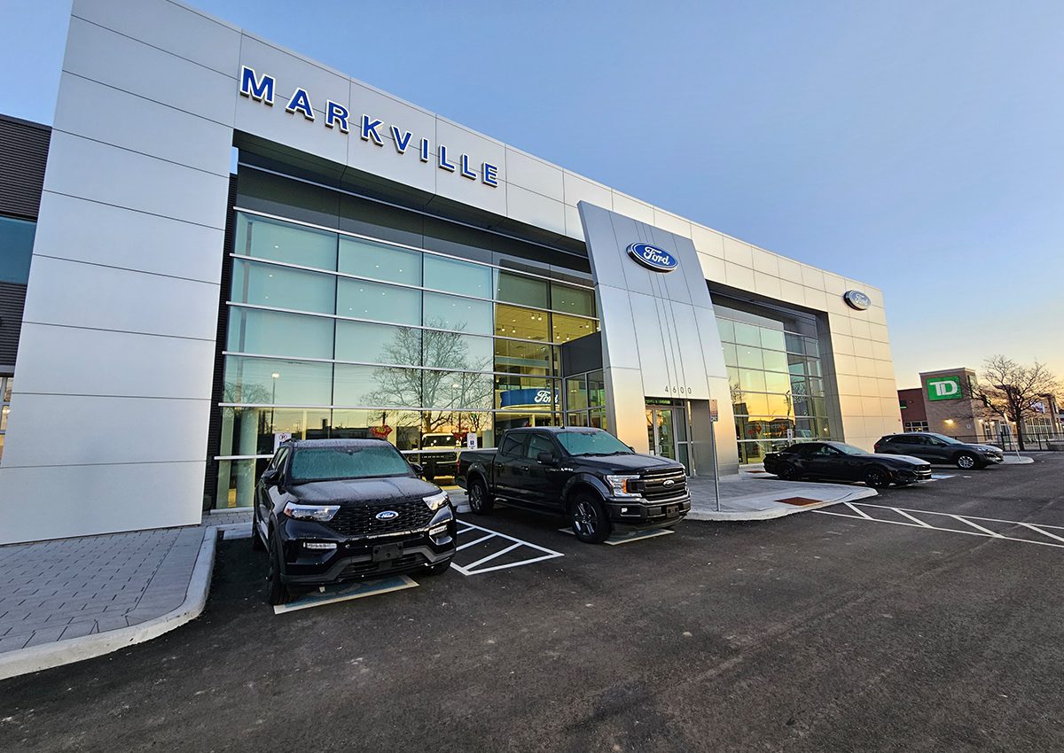 Modern car dealership with multiple cars parked outside under a clear sky.