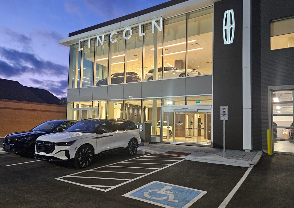 Lincoln dealership building with a white car parked outside at dusk.