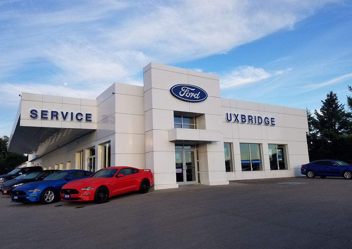 Ford dealership building with a red car parked outside.