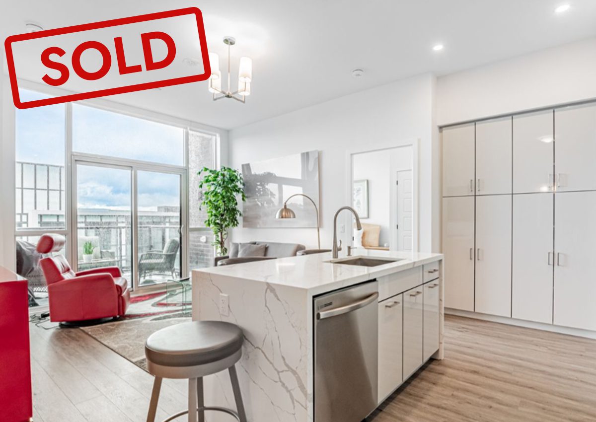 Modern kitchen with marble island and city view, marked as sold.