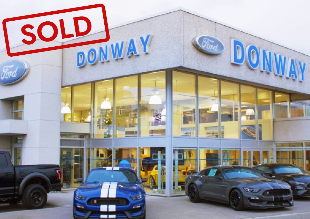 Car dealership with a sold sign and cars parked outside.