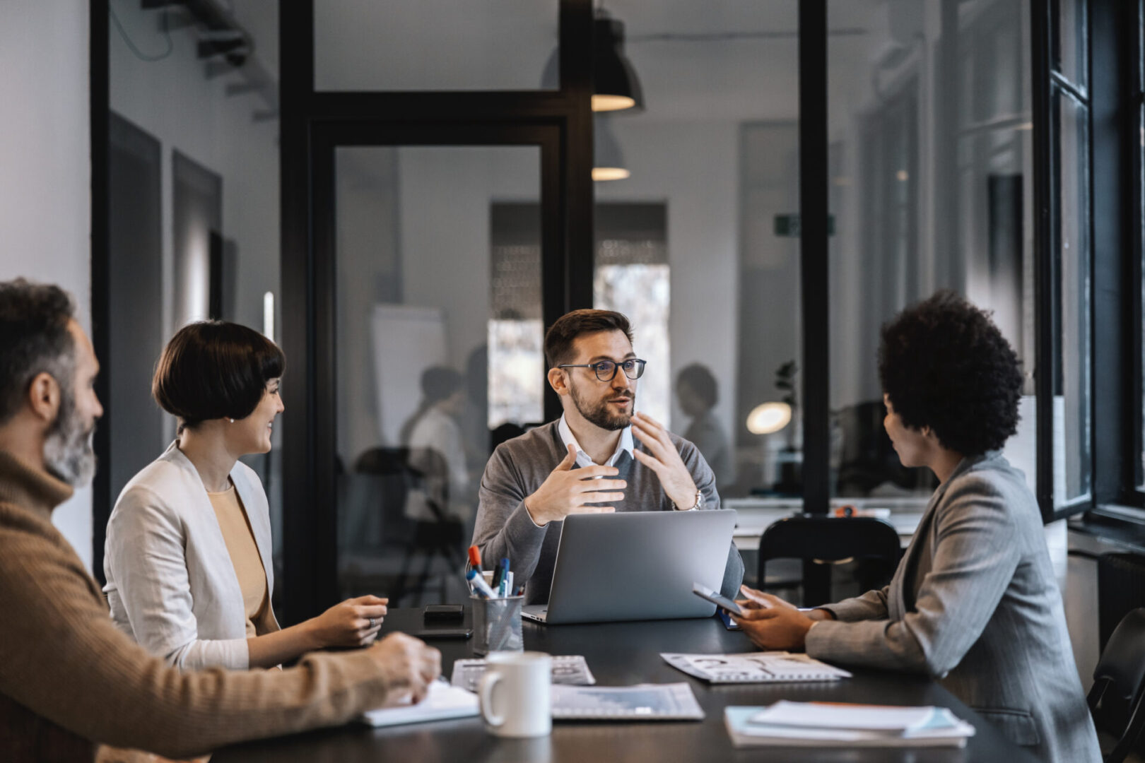A man leading a business meeting with colleagues in an office.