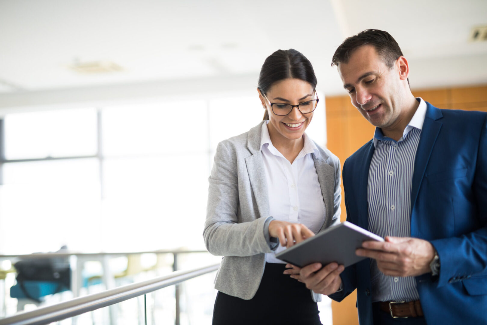 Two professionals reviewing documents together in a bright office.