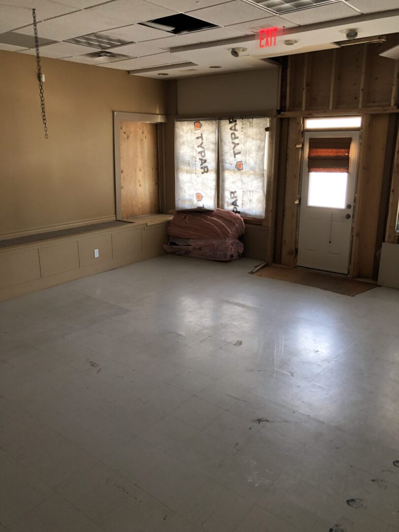 Empty room with bare walls and a window covered by curtains.