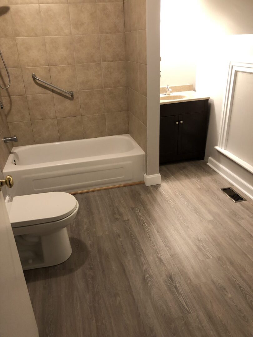 Modern bathroom with wood-look flooring and white fixtures.