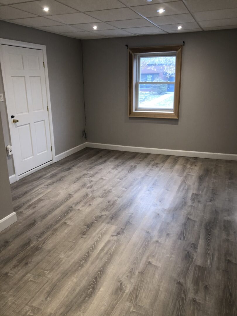 Empty room with wood-look flooring and a window.