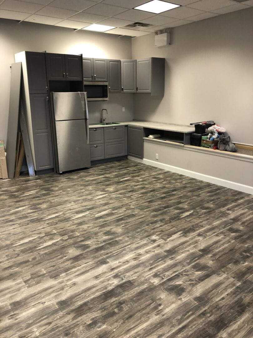 Modern kitchen corner with stainless steel appliances and gray wood flooring.
