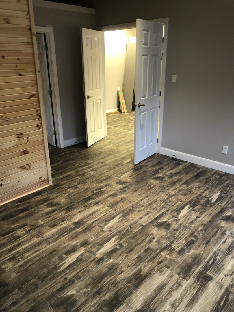 Empty room with wood-look flooring and white door.