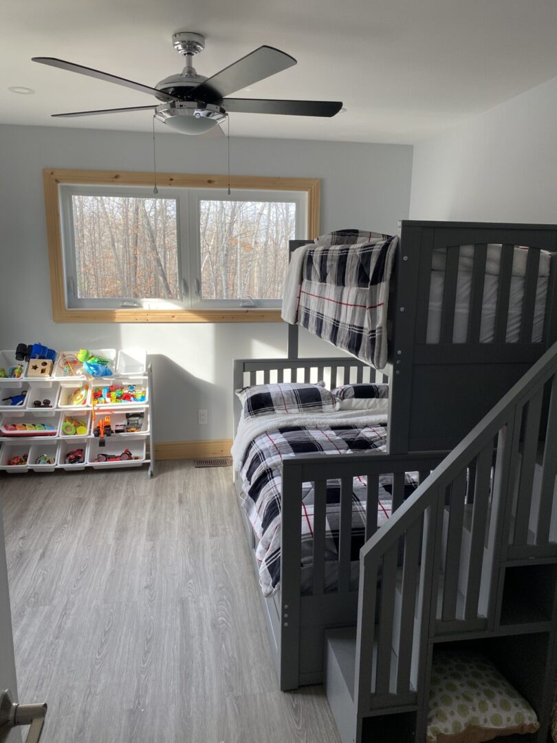 Cozy bedroom with black-and-white bunk beds and organized toy bins under a bright window.
