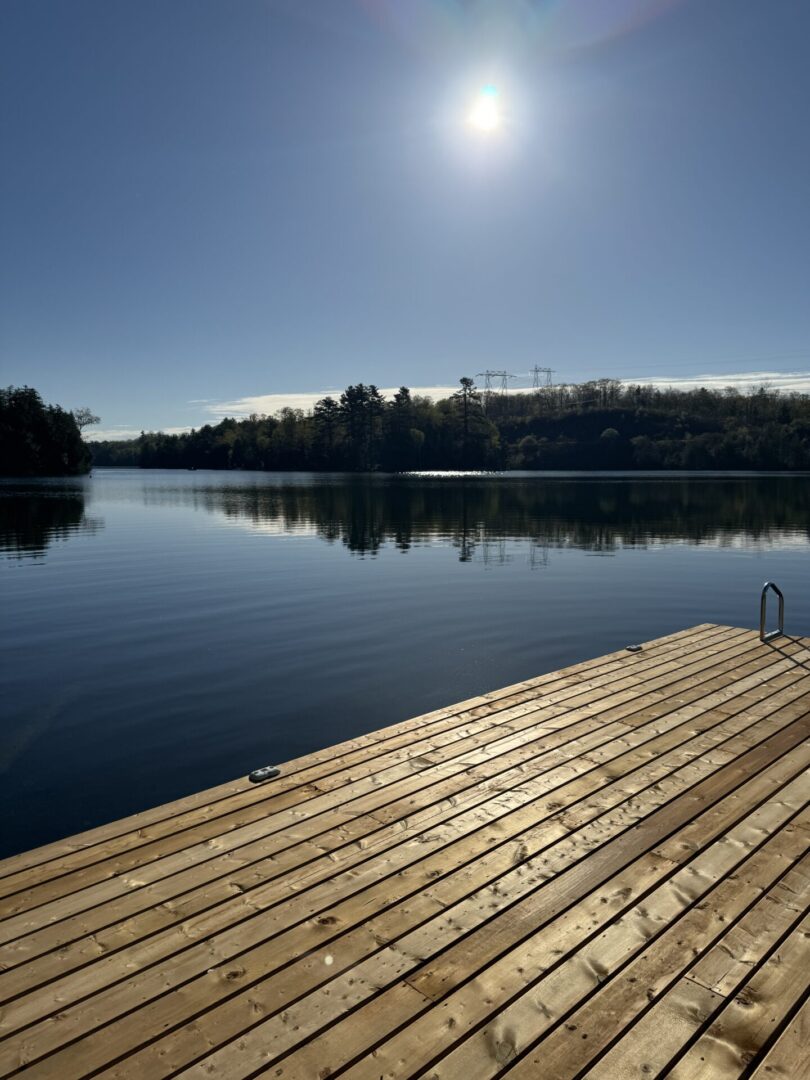 A calm lake with a wooden dock under a clear sky.