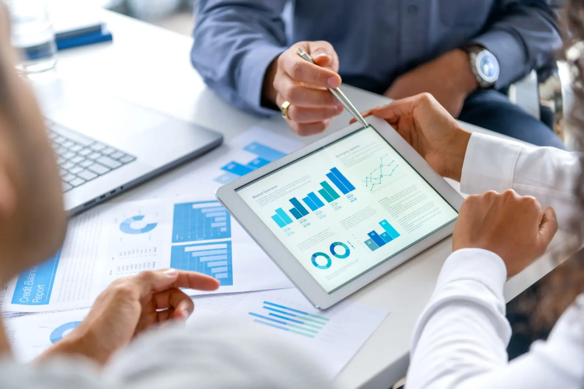 Business professionals analyzing financial data on a tablet during a meeting.